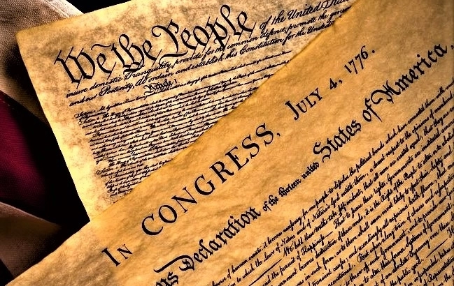 The United States Constitution and Declaration of Independence on an American Flag background