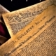 The United States Constitution and Declaration of Independence on an American Flag background