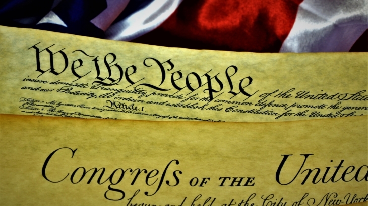 United States Constitution showing the first page with Article I, with the Bill of Rights and American Flag