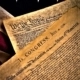 The United States Constitution and Declaration of Independence on an American Flag background