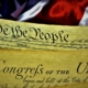 United States Constitution showing the first page with Article I, with the Bill of Rights and American Flag
